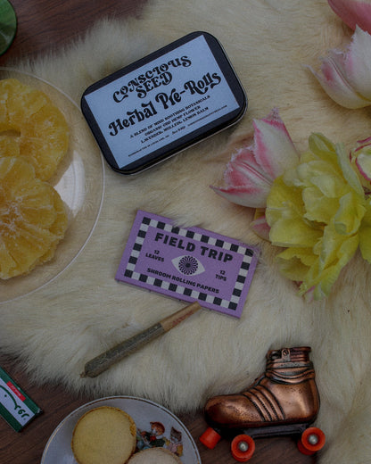 The image displays a box of CBD Herbal Pre-Rolls titled 'Uplifting Smoke Blend,' alongside flowers and field trip rolling papers. A natural and enjoyable CBD smoke blend.