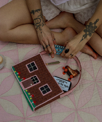Person sitting on a vintage quilt with a stash bag, toy roller skate lighter, and Conscious Seed pre rolls.